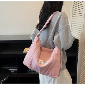 Rosa Cord-Umhängetasche mit verstellbarem Riemen und Vordertasche am Modell getragen