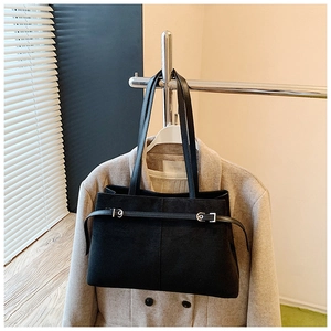 Gros plan d'un sac cabas en daim noir mat avec boucle en métal sur un porte-manteau