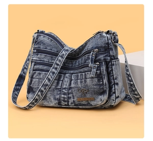 Close-up of retro washed denim crossbody bag featuring multiple zipper pockets and metal logo