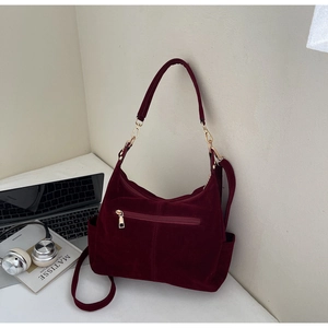 Detailed view of a dark red suede tote bag with gold zippers and dual shoulder straps