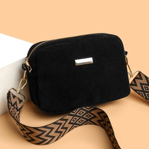 Minimalist black matte crossbody camera bag with patterned jacquard strap on white stand