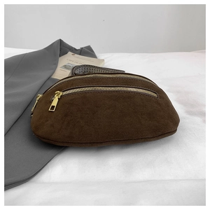 Detail of dark brown suede fanny pack with golden zippers and wide black strap