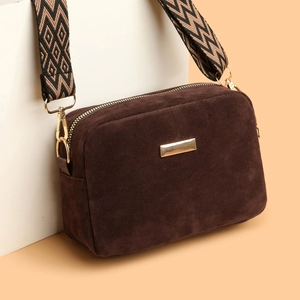 Brown faux suede crossbody bag with geometric woven strap on a minimalist background