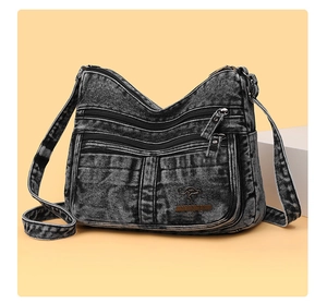 Detail of dark gray washed denim bag with multiple zippers and brand plaque