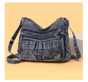 Close-up of vintage blue denim crossbody bag with multiple zippers and metal kangaroo logo