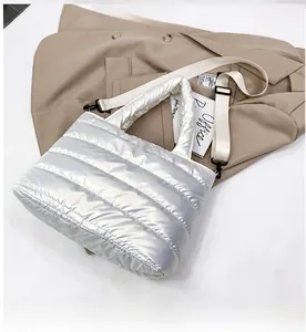 Detalle de bolso acolchado plateado con correa ancha para hombro y asas suaves