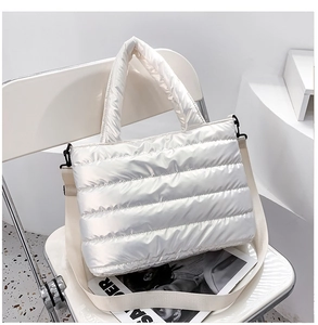 Primer plano de bolso acolchado plateado brillante con correa ancha en una silla