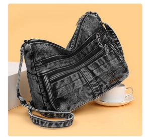 Detail of multi-layer denim crossbody bag with golden kangaroo logo and metal zippers