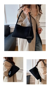 Detail einer schwarzen Wildleder-Baguette-Tasche mit matter Textur und Tropfen-Anhänger