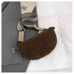 Detail of coffee brown saddle bag with geometric patterned wide strap on a gray suit