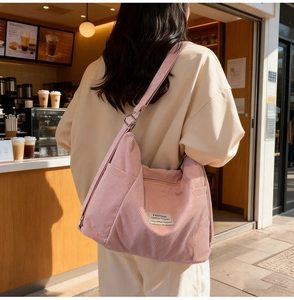 Detailstruktur der rosa Cord-Umhängetasche mit vielen Taschen am Model gezeigt