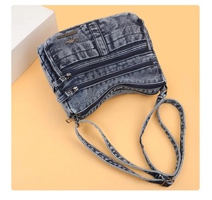 Detail view of denim crossbody bag with triple zippers and kangaroo logo on orange background