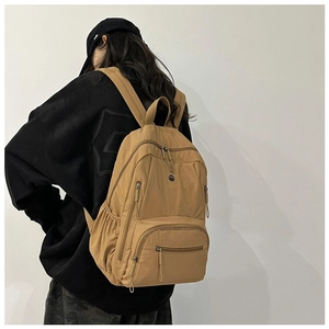 Detailed back view of khaki nylon travel backpack with multiple pockets on a female model