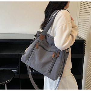 Détail du sac fourre-tout gris en velours côtelé avec poches zippées et texture fine