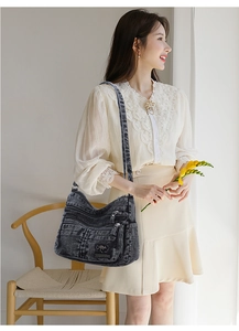 Detailed view of grey washed denim crossbody bag with multiple zipper pockets on a model