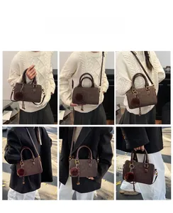 Détail du sac Boston marron foncé avec pompon en fourrure et bandoulière amovible