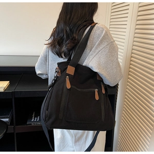 Détail du sac bandoulière en velours côtelé noir avec poche zippée et détails en cuir
