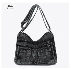 Detail of black denim multi-layer crossbody bag showing zippers and brand logo