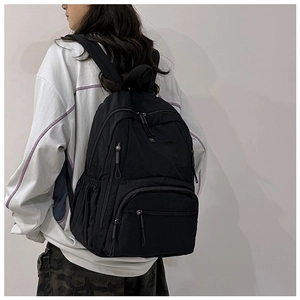Detailed view of black nylon multi-pocket backpack showing zippers and side pouches