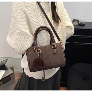 Sac Boston marron avec breloque en peluche présenté dans un style de vie moderne
