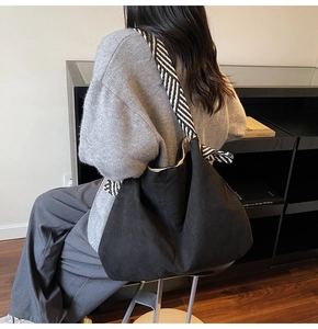 Close-up of black slouchy bucket bag with stylish black and white striped shoulder strap
