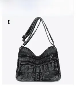 Detail of black washed denim crossbody bag featuring multi-layer zippers and kangaroo logo