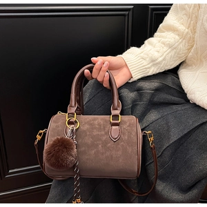 Détail du sac Boston en daim marron foncé avec pompon en peluche et ruban à pois