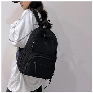 Side view of multi-pocket black nylon backpack for women shown on a model