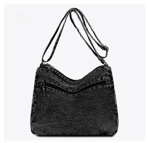 Detail view of the back of a washed denim crossbody bag featuring dual parallel zipper pockets
