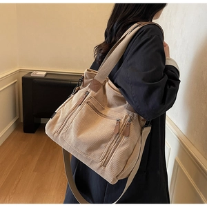 Détail du sac bandoulière en velours côtelé avec poches zippées et étiquette de marque