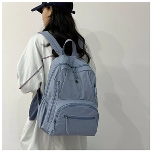 Detail of grey-blue nylon backpack with multi-pocket design and adjustable side straps
