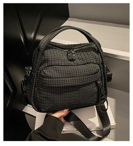 Detail of checkered nylon crossbody bag featuring front zip pocket and sturdy handle