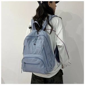Side view of light blue nylon multi-pocket backpack worn by a model on plain white background