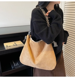 Detail view of large brown faux suede tote bag with stylish striped woven shoulder strap