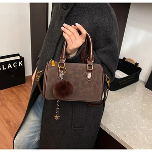 Détail du sac Boston vintage marron foncé avec pompon en fourrure et poignées en cuir chic