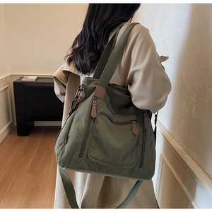 Vue détaillée du grand sac bandoulière en velours côtelé vert avec plusieurs poches zippées