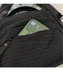 Close-up of black checkered nylon crossbody bag showing the front zipper pocket capacity