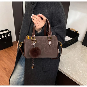 Détail du sac Boston marron foncé avec pompon en fourrure et finitions dorées