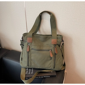 Détail d'un sac cabas en velours côtelé vert avec plusieurs poches zippées sur fauteuil