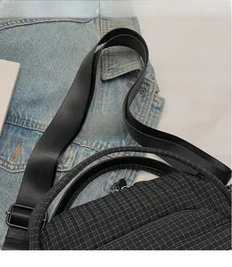 Close-up of adjustable woven shoulder strap and metal buckle on black nylon crossbody bag
