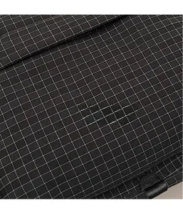 Macro detail of lightweight black checkered nylon fabric on a casual crossbody bag