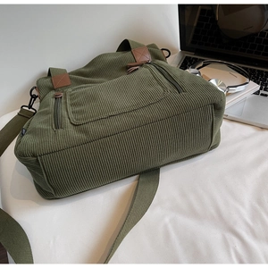 Détail du cabas en velours côtelé vert olive avec poignées en cuir et poches zippées
