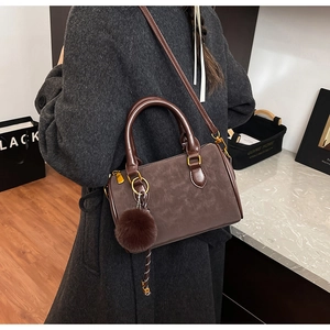 Sacoche rétro marron foncé avec pompon présenté sur modèle pour échelle de taille