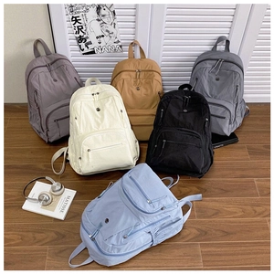 Multiple colors of nylon backpacks with multi-pocket design on a wooden floor