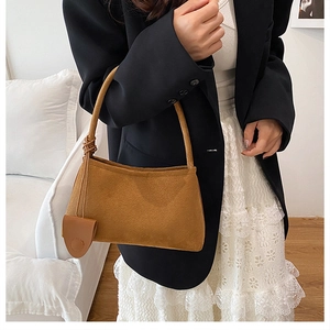Detailansicht der braunen Wildleder-Achseltasche mit passendem Beutel am Model-Outfit