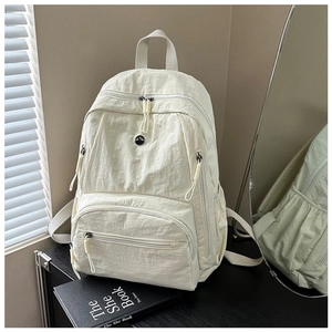 Detailed view of cream nylon backpack with multiple pockets and wrinkled texture finish