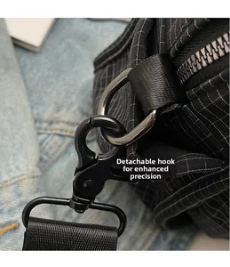 Close-up of detachable metal hook and black nylon strap on checkered shoulder bag