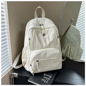 Detail of ivory nylon backpack with multiple zippered pockets and textured fabric finish