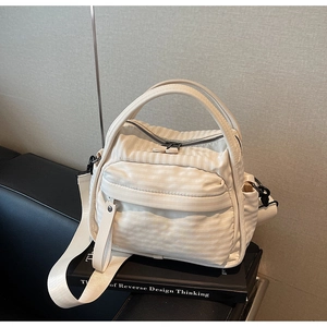 Detail of off-white nylon crossbody bag with striped texture and wide shoulder strap