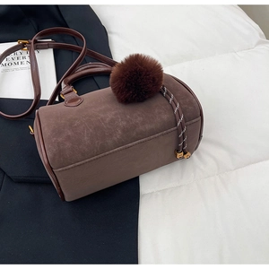 Détail du sac Boston vintage marron avec pompon en peluche et pendentif en corde tressée